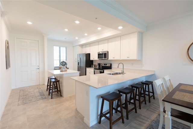 kitchen featuring sink, stainless steel appliances, white cabinets, and a breakfast bar area