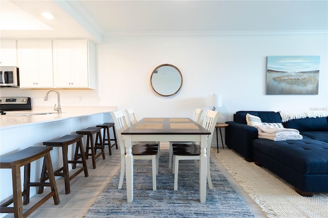 tiled dining area featuring sink and crown molding