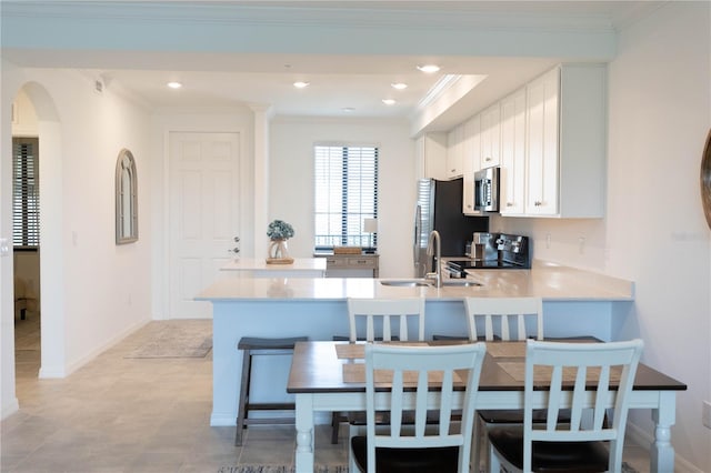 kitchen with kitchen peninsula, a breakfast bar, white cabinets, and sink