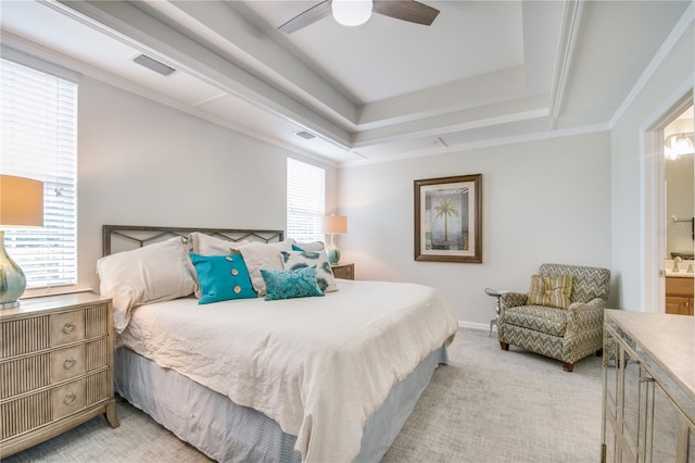 bedroom with a tray ceiling, light carpet, ensuite bathroom, and multiple windows