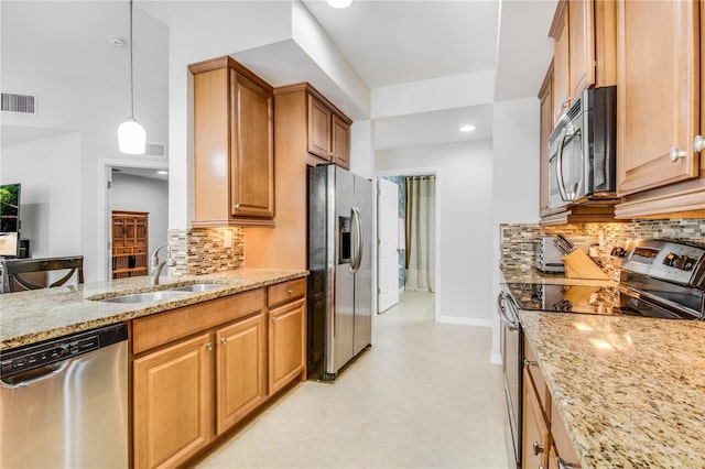 kitchen featuring sink, tasteful backsplash, stainless steel appliances, pendant lighting, and light stone countertops