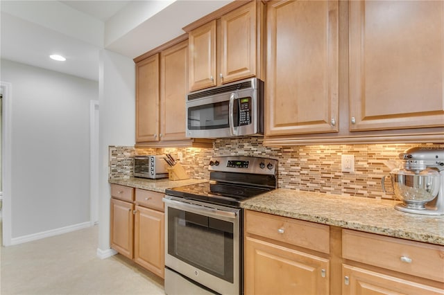 kitchen featuring light stone countertops, light brown cabinets, backsplash, appliances with stainless steel finishes, and light tile floors