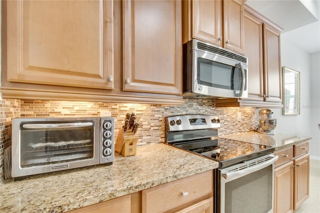 kitchen with light stone counters, appliances with stainless steel finishes, tasteful backsplash, and light brown cabinets