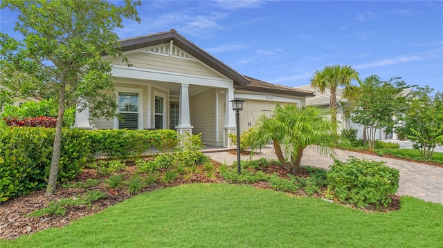 view of front of home featuring a garage, covered porch, and a front lawn