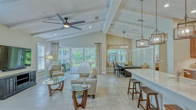 tiled living room featuring lofted ceiling with beams, sink, and ceiling fan with notable chandelier