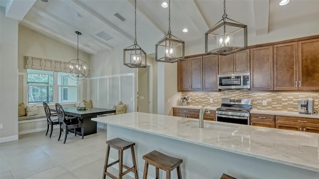 kitchen with light stone countertops, decorative light fixtures, stainless steel appliances, light tile flooring, and sink