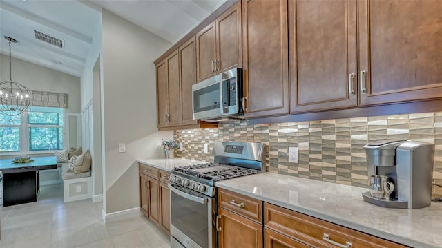 kitchen with light stone countertops, backsplash, stainless steel appliances, lofted ceiling, and a chandelier