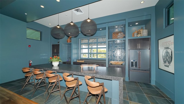 kitchen featuring high end refrigerator, a kitchen bar, hanging light fixtures, dark hardwood / wood-style floors, and kitchen peninsula