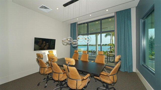 dining area with a water view and carpet