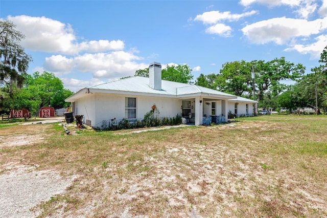 back of property featuring a storage unit and a lawn