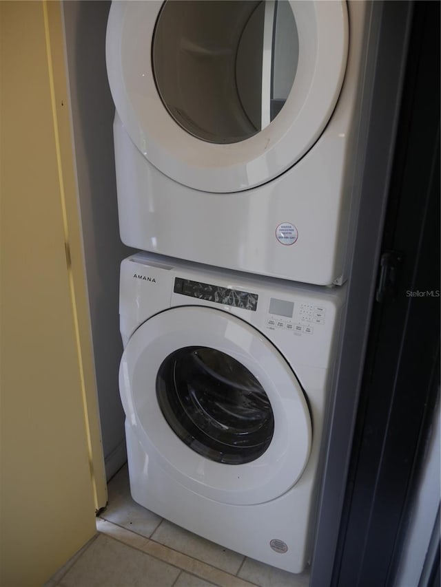 washroom with stacked washer / drying machine and light tile patterned floors