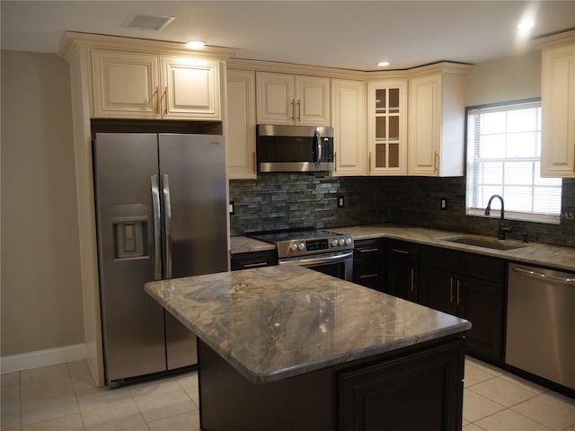 kitchen with light tile patterned flooring, stainless steel appliances, a kitchen island, and sink