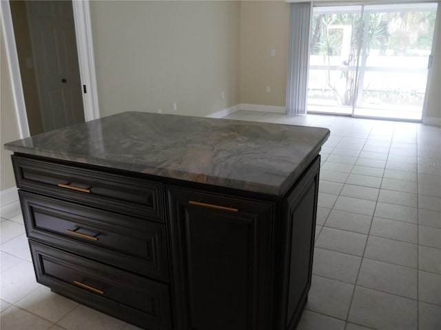 kitchen with light tile patterned floors, a center island, and dark stone countertops