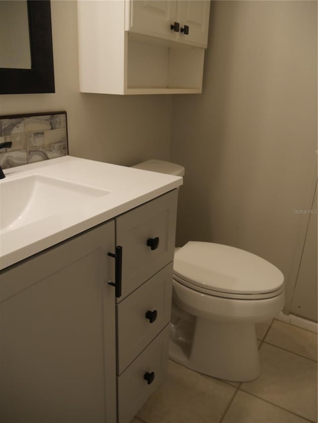 bathroom with toilet, vanity, and tile patterned floors