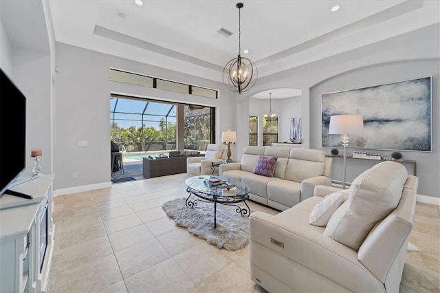 tiled living room featuring a raised ceiling and an inviting chandelier