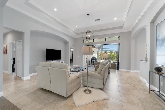 tiled living room with a raised ceiling, a notable chandelier, and ornamental molding