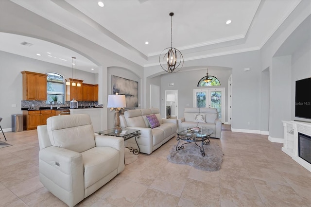 living room with an inviting chandelier, light tile floors, and a tray ceiling