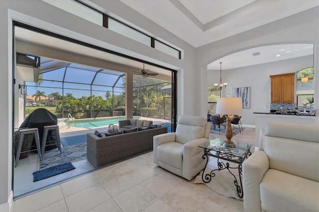 tiled living room featuring a wealth of natural light, an inviting chandelier, and a tray ceiling