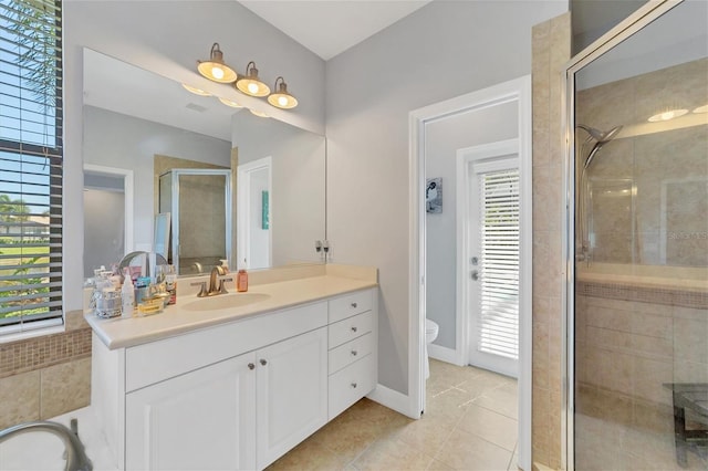 bathroom featuring a shower with door, toilet, tile floors, and vanity