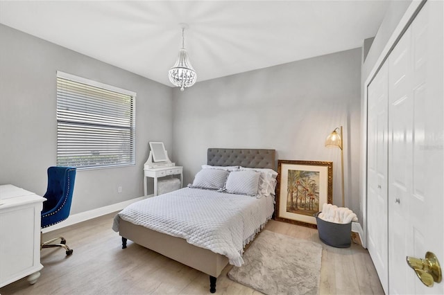 bedroom featuring a closet, light hardwood / wood-style floors, and a chandelier