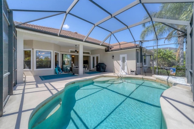 view of pool featuring a patio, glass enclosure, and ceiling fan