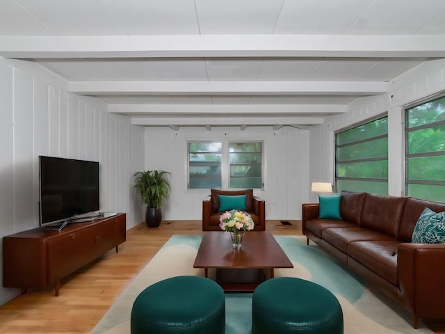 living room featuring wood walls, beam ceiling, and light wood-type flooring