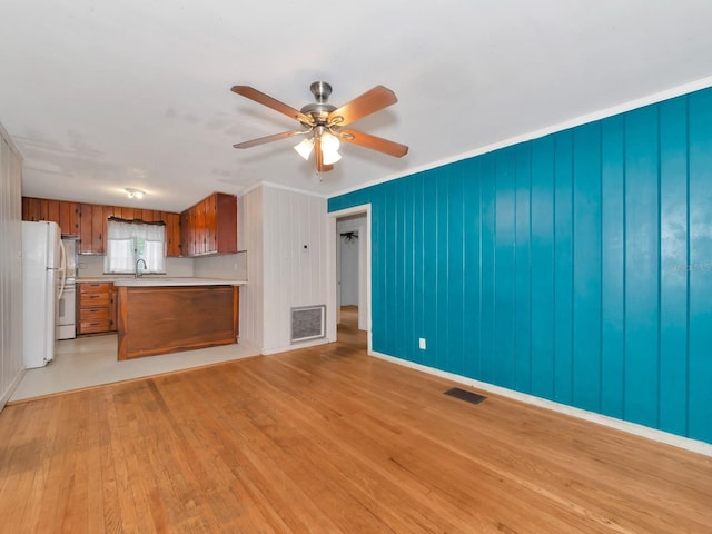 unfurnished living room with sink, light hardwood / wood-style flooring, and ceiling fan