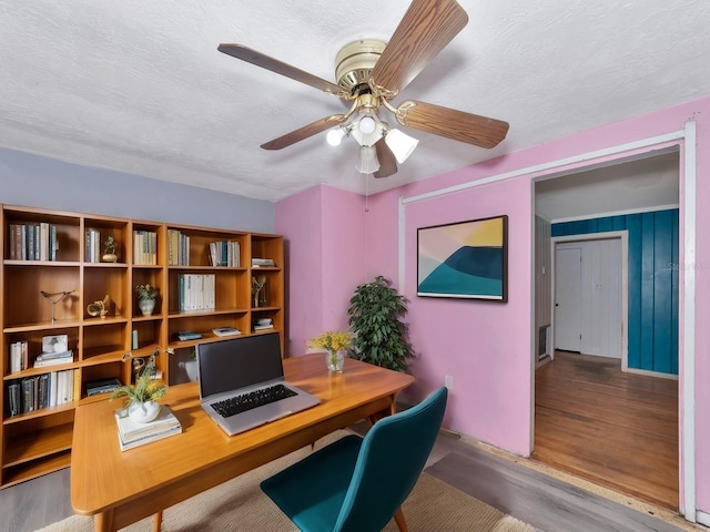 home office with ceiling fan, wood-type flooring, and a textured ceiling