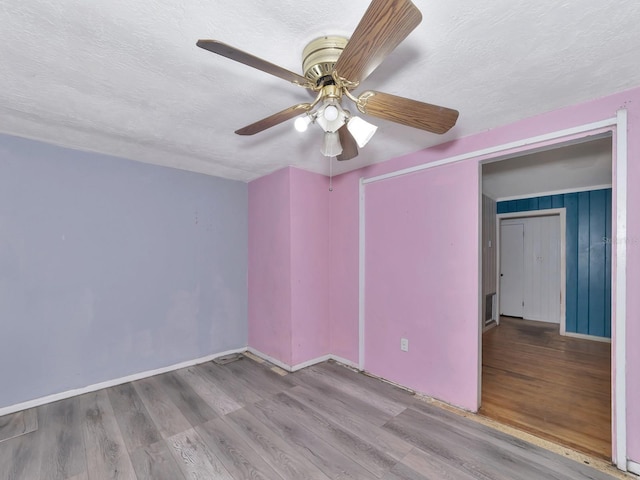 empty room featuring ceiling fan, a textured ceiling, and light wood-type flooring