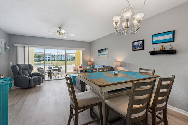 dining room featuring ceiling fan with notable chandelier and wood-type flooring