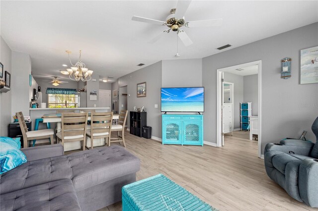 living room featuring ceiling fan with notable chandelier and light hardwood / wood-style flooring