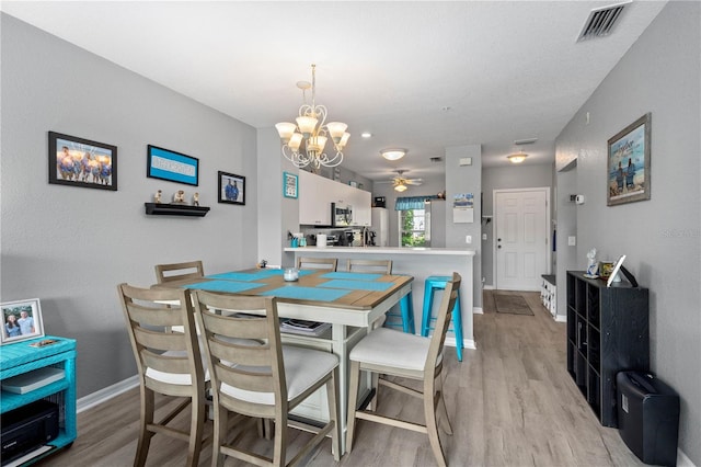 dining area featuring light wood-type flooring and ceiling fan with notable chandelier