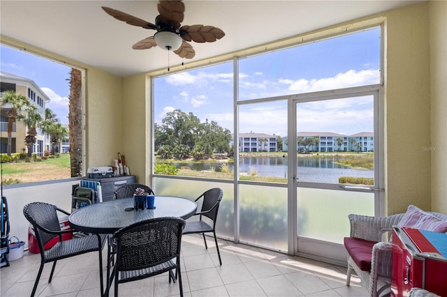 sunroom with plenty of natural light, ceiling fan, and a water view