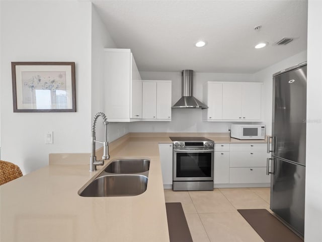 kitchen with white cabinets, sink, wall chimney range hood, light tile flooring, and stainless steel appliances