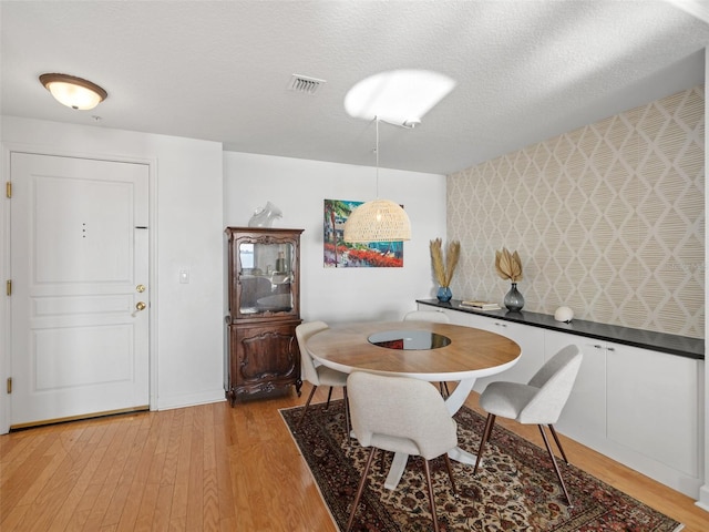 dining room with light hardwood / wood-style floors and a textured ceiling