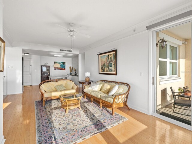 living room featuring ornamental molding, ceiling fan, and light wood-type flooring