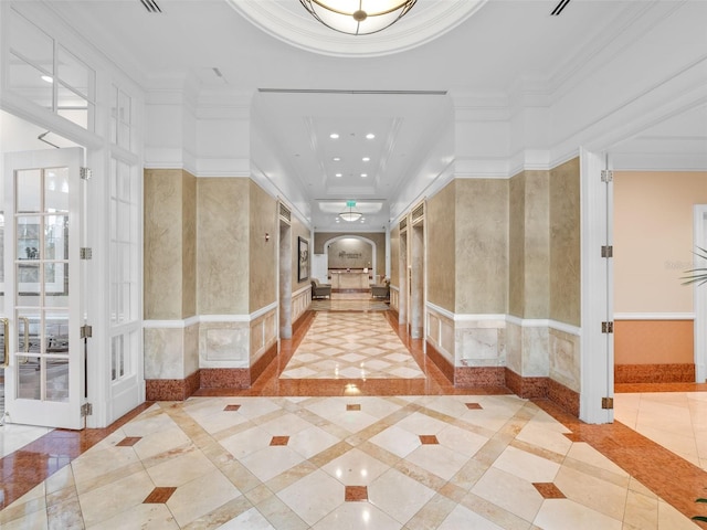 hallway with crown molding, light tile floors, and a tray ceiling