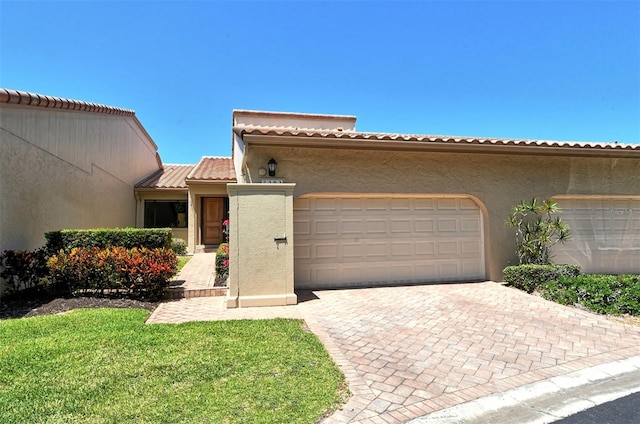 mediterranean / spanish house with a garage and a front lawn