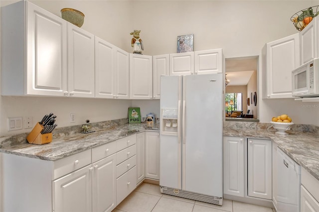 kitchen with white appliances, light tile floors, and white cabinetry