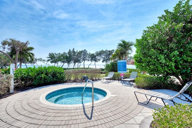 view of pool featuring a water view, a patio, and a hot tub