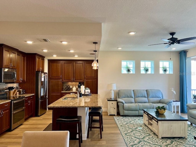 kitchen featuring a kitchen bar, backsplash, stainless steel appliances, and a center island with sink