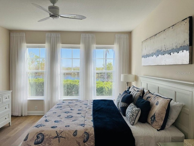 bedroom featuring light wood-type flooring, multiple windows, and ceiling fan