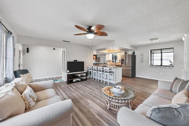 living room featuring ceiling fan, wood-type flooring, and a textured ceiling