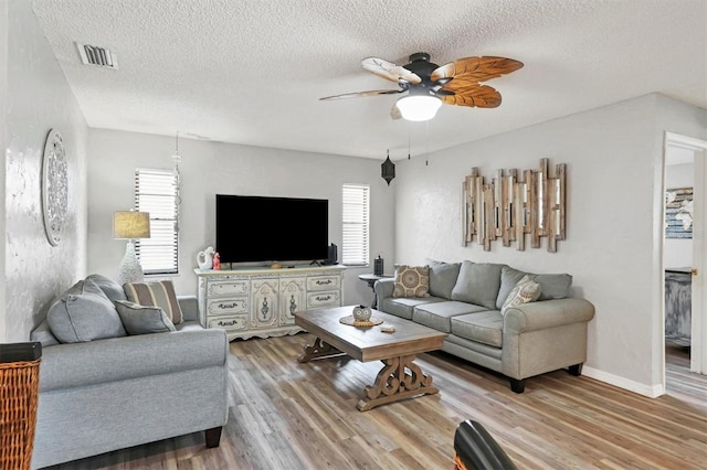 living room with ceiling fan, a healthy amount of sunlight, wood-type flooring, and a textured ceiling