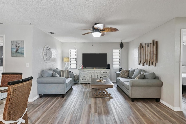 living room featuring ceiling fan, wood-type flooring, and a textured ceiling