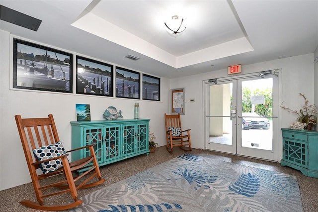 sitting room with a raised ceiling, french doors, and carpet