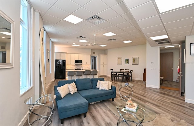 living room with a paneled ceiling and light hardwood / wood-style flooring