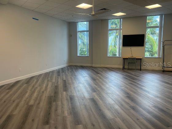 unfurnished living room featuring dark hardwood / wood-style flooring, plenty of natural light, and a paneled ceiling