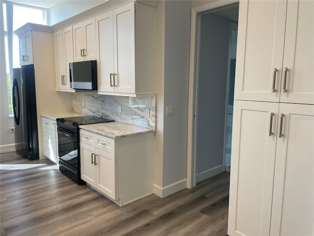 kitchen featuring backsplash, black range with electric stovetop, fridge, light stone counters, and white cabinetry