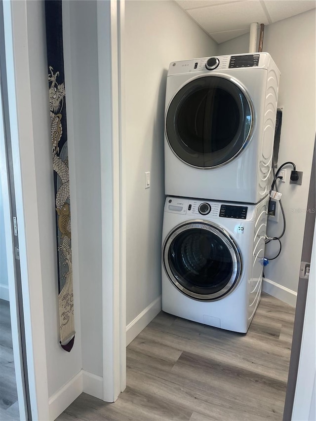 washroom featuring stacked washing maching and dryer and light hardwood / wood-style flooring